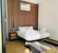 Schlafzimmer in einem Einfamilienhaus mit gemusterter Wand, Ventilator, Teppich und Boden in Holzoptik.