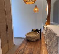 Innenraum eines Einfamilienhauses mit einem Waschbecken aus Stein, einer Holzplatte und Hängelampen.