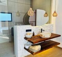 Badezimmer im Einfamilienhaus mit Waschbecken auf einem Holzregal und Boden mit Holzdekor.