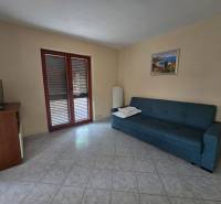 Wohnzimmer in einer besonderen Immobilie mit Sofa, TV-Schrank und gefliestem Boden.