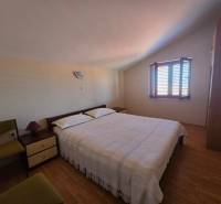 Ein Schlafzimmer mit Licht, das durch das Fenster fällt, einem Bett und einem Boden mit Holzdekor.