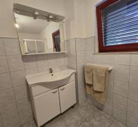 Badezimmer mit hellen Fliesen, Spiegel und Waschtischunterschrank, Besondere Immobilien.