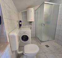 Ein Badezimmer ausgestattet mit einer Waschmaschine, einer Duschkabine und einem Boiler in Besonderen Immobilien.