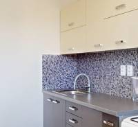 Küche mit Mosaikfliesen in einer 2-Zimmer-Wohnung, mit Holzdekor der Küchenschränke.