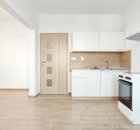 Küche in einer 2-Zimmer-Wohnung mit weißen Schränken, Herd und Boden in Holzoptik.