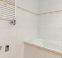 Badezimmer mit Badewanne und weißen Fliesen in einer 2-Zimmer-Wohnung.