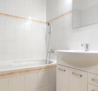 Badezimmer in einer 2-Zimmer-Wohnung mit weißen Fliesen und Badewanne.