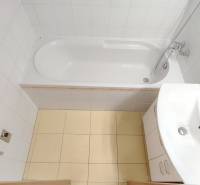 Badezimmer in einer 2-Zimmer-Wohnung mit Badewanne, Waschbecken und weißen Fliesen.