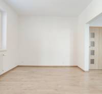 Wohnzimmer in einer 2-Zimmer-Wohnung mit Holzboden und Küchenzeile.