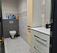 Badezimmer in einer 3-Zimmer-Wohnung mit hängendem WC, Waschbecken, Schrank und hellen Fliesen.