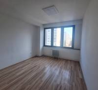 Ein Büro mit einem Holzboden und einem großen Fenster in der Tulska-Straße in Zvolen.