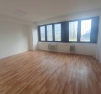 Innenraum eines Büros mit Holzboden und großen Fenstern.