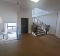 Eine Treppe in Geschäftsräumen mit Fenstern und einem Boden in Holzoptik.