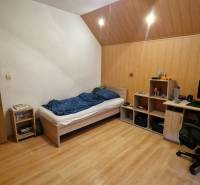 Ein Zimmer in einer 3-Zimmer-Wohnung mit einem Bett, einem Schreibtisch und einem Boden mit Holzdekor.