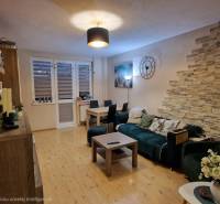 Wohnzimmer in einer 3-Zimmer-Wohnung mit Holzboden und dekorativen Elementen.