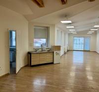 Büros mit Holzboden, großen Fenstern und einer Kochnische.