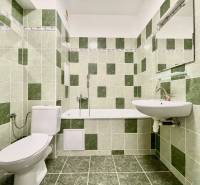 Badezimmer in der Východná-Straße mit grünen Fliesen, Badewanne, Waschbecken und Toilette in einer 2-Zimmer-Wohnung.