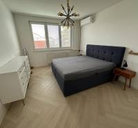 Schlafzimmer mit Bett, weißer Kommode, Holzboden und Hängelampe.