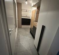 Flur in einer 2-Zimmer-Wohnung mit Fliesen, Schränken und Holzvertäfelungen.