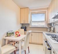 Küche in einer 4-Zimmer-Wohnung mit Esstisch, cremefarbenen Stühlen und Küchenzeile.