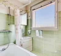 Badezimmer in einer 4-Zimmer-Wohnung mit Badewanne, grünen Fliesen und Spiegel.