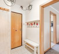 Eingangsflur in einer 4-Zimmer-Wohnung, weiße Wände, Kleiderhaken und Bank.