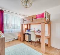 Kinderzimmer mit einem Hochbett, einem Boden in Holzoptik und Spielzeug auf den Regalen.