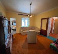 Wohnzimmer eines Einfamilienhauses mit älteren Möbeln, Sofa und Teppich.