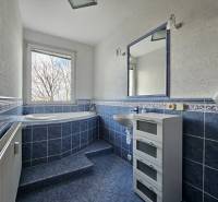Ein Badezimmer mit blauen Fliesen und einer großen Badewanne in einer 3-Zimmer-Wohnung.