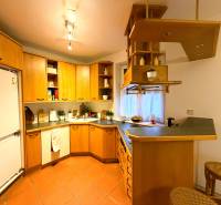 Küche in einer 3-Zimmer-Wohnung mit Holzschränken und Bartheke.