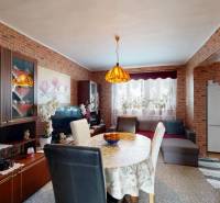 Esszimmer in einer 4-Zimmer-Wohnung mit Möbeln, einem Tisch mit Tischdecke und Ziegelverkleidung.