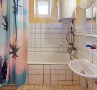 Badezimmer in einer 4-Zimmer-Wohnung mit Badewanne, farbigem Vorhang und gefliester Wand.