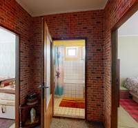 Der Flur einer 4-Zimmer-Wohnung mit Ziegelverkleidung, der zu den Schlafzimmern und dem Badezimmer führt.