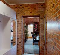 Flur in einer 4-Zimmer-Wohnung mit Ziegelwänden und Flurmöbeln.