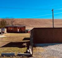 Baucontainer in der Straße Prosačov in Prosačov, umgeben von kleinen Bäumen und einem Zaun.
