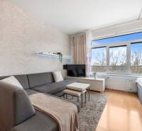 Wohnbereich einer Einzimmerwohnung mit Sofa, Fernseher, hellen Wänden und Boden in Holzoptik.