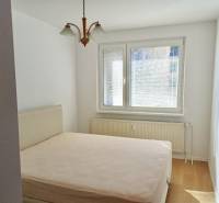 Helles Schlafzimmer mit Doppelbett und Kronleuchter in einer 3-Zimmer-Wohnung, Boden mit Holzdekor.