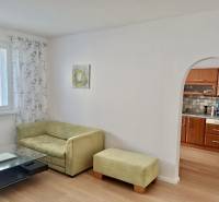 Wohnzimmer in einer 3-Zimmer-Wohnung mit Sofa, Tisch und einem Bogen zur Küche.