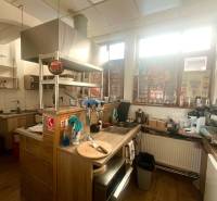 Eine Küche in gastronomischen Räumlichkeiten mit einem Boden in Holzoptik, ausgestattet mit modernen Geräten.