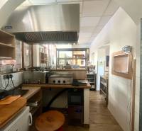 Küchenbereich mit Edelstahl-Dunstabzugshaube und Holzboden in Gastronomiebereichen.