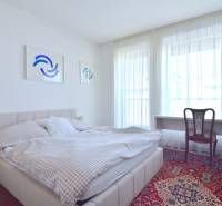 Schlafzimmer in einer 3-Zimmer-Wohnung mit Bett, Tisch und Kunstwerken an der Wand.