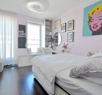 Schlafzimmer in einer 3-Zimmer-Wohnung mit Holzboden und Kunstbildern an der Wand.