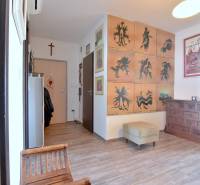 Flur in einer 3-Zimmer-Wohnung mit Sesseln, Bildern und einem Boden in Holzoptik.