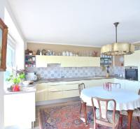 Küche in einer 3-Zimmer-Wohnung mit Holzmöbeln, Blumen und gemustertem Teppich.