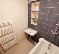 Badezimmer in einer 4-Zimmer-Wohnung mit Badewanne, Waschbecken und Ablagefächern.