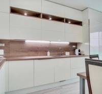 Küche in einer 3-Zimmer-Wohnung mit weißen Möbeln und einem Boden in Holzoptik.