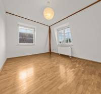 Ein Zimmer in einem Einfamilienhaus mit weißen Wänden und einem Boden in Holzoptik.