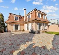 Ein Einfamilienhaus in Bratislava-Záhorská Bystrica mit einem gepflasterten Hof und einem gepflegten Garten.