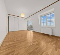 Ein Zimmer in einem Einfamilienhaus mit einem Boden in Holzoptik, einem Holzbalken und großen Fenstern.