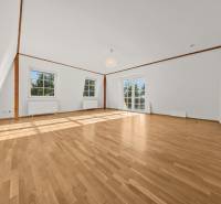 Heller Raum mit Holzboden und großen Fenstern in einem Einfamilienhaus.